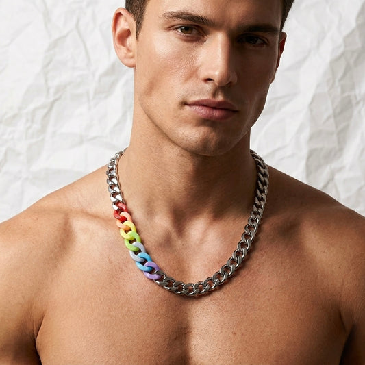 A close-up of a shirtless man wearing a chunky silver chain necklace with a distinctive rainbow-colored link accent on one side, set against a textured white background.